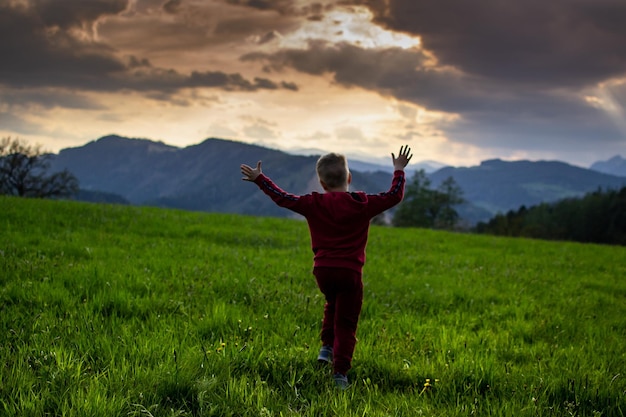 il ragazzino corre nei raggi del tramonto, facendo un'escursione in montagna