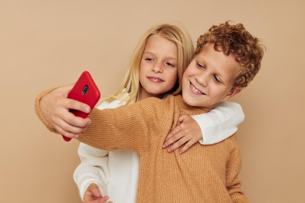 Il ragazzino e la ragazza con un telefono rosso insieme tecnologie hanno isolato lo sfondo