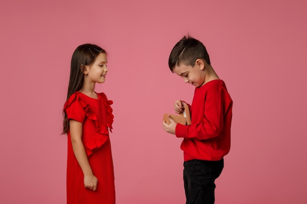 Il ragazzino felice del bambino dà alla ragazza sorridente un contenitore di regalo