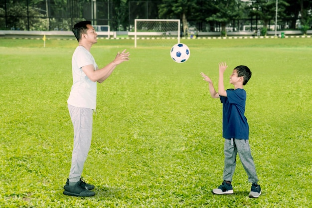 Il ragazzino felice lancia una palla a suo padre