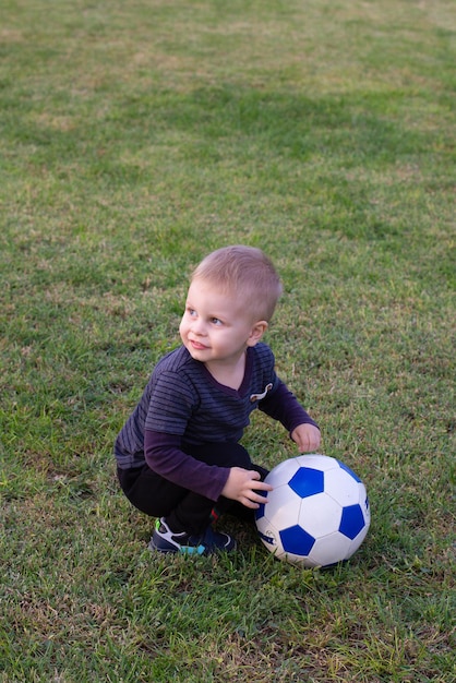 Il ragazzino gioca a calcio sul campo di calcio dà un passaggio colpisce la palla attraversa il campo e segna un goal sport bambino calciatore si allena all'aria aperta