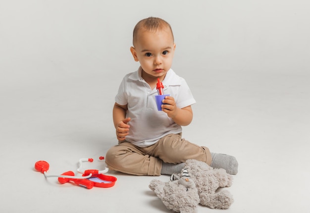 Il ragazzino gioca al dottore e tratta un peluche con uno stetoscopio. Bambini e medicina, assistenza sanitaria. foto in studio di alta qualità