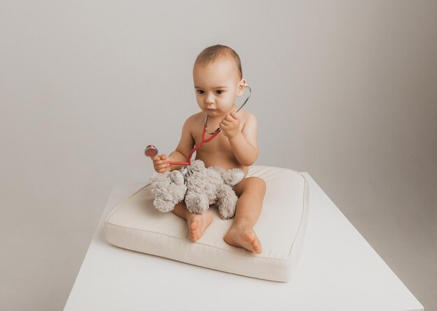 Il ragazzino gioca al dottore e tratta un peluche con uno stetoscopio. Bambini e medicina, assistenza sanitaria. foto in studio di alta qualità