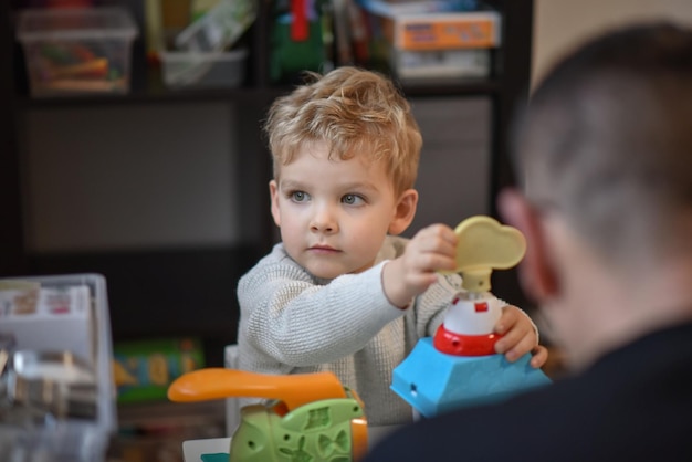 Il ragazzino gioca con il padre nella stanza dei bambini e guarda fuori dalla finestra.