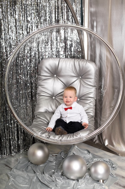 Il ragazzino gioca su una sedia una ciotola di vetro con palline d'argento