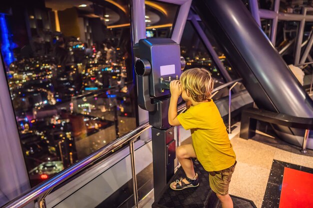 Il ragazzino guarda il paesaggio urbano di Kuala Lumpur Vista panoramica dello skyline della città di Kuala Lumpur sera al tramonto grattacieli che costruiscono in Malesia Viaggiare con il concetto di bambini