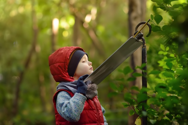 Il ragazzino legge un cartello esplicativo nello zoo o nel parco della natura.