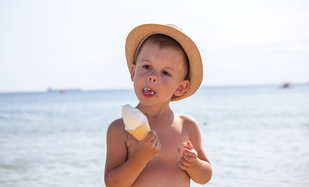 Il ragazzino mangia il gelato sulla spiaggia Fuoco selettivo di riposo