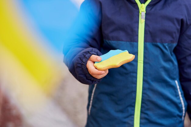 Il ragazzino patriottico mangia il biscotto simbolico ucraino blu e giallo Spazio di copia Stand con l'Ucraina Sostieni l'Ucraina Ferma il concetto di aggressione russa Ferma la guerra in Ucraina Prega per l'Ucraina