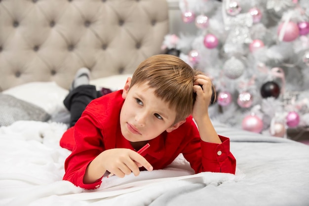 Il ragazzino scrive una lettera a Babbo Natale pensa ai regali per Natale