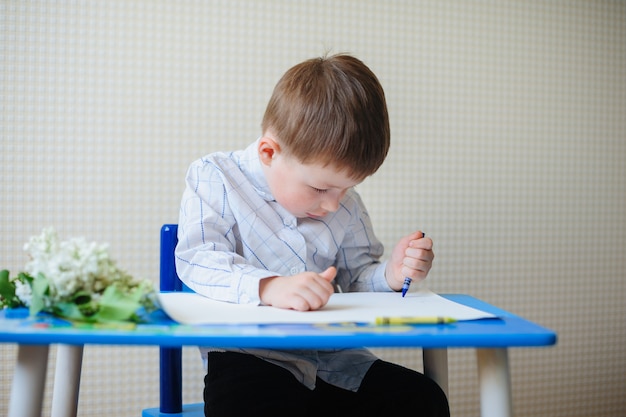 Il ragazzino seduto alla scrivania disegna