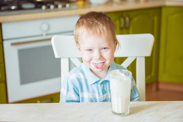 Il ragazzino sorridente mostra la lingua, macchiata di latte