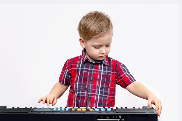 Il ragazzino suona il pianoforte digitale Il bambino concentrato studia a casa Il concetto di sviluppo della prima infanzia