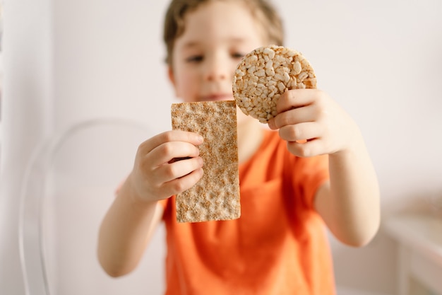 Il ragazzino sveglio mangia il concetto di stile di vita e di nutrizione sano del pane croccante
