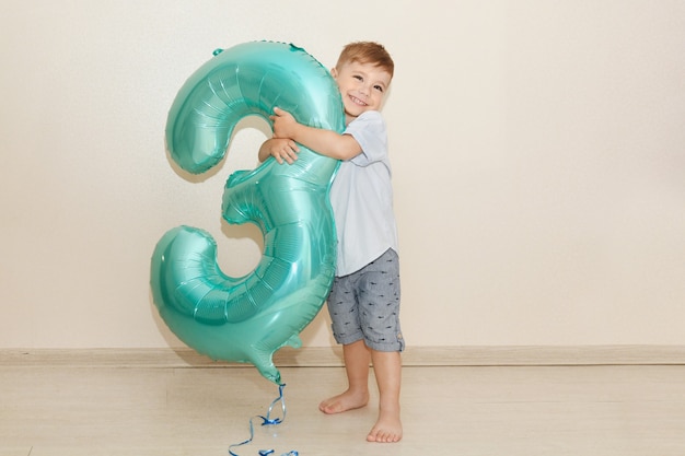 Il ragazzo abbraccia il numero tre per il suo compleanno