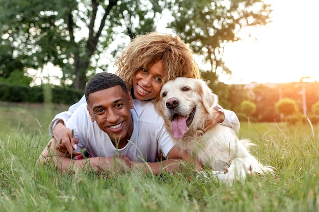 Il ragazzo afroamericano con la ragazza si trova insieme al golden retriever nel parco