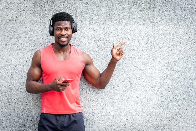 Il ragazzo afroamericano in cuffia ascolta musica all'aperto contro un muro