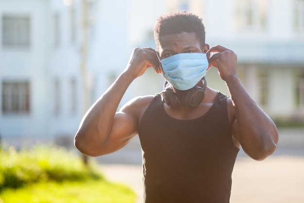 Il ragazzo afroamericano indossa una maschera medica all'aperto sullo sfondo della città