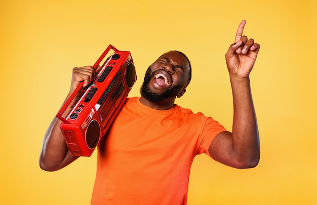 Il ragazzo ascolta la musica con un vecchio stereo e balla. espressione emotiva ed energetica. muro giallo