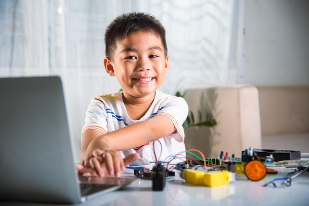 Il ragazzo asiatico impara la codifica e la programmazione con il laptop per l'auto robotica Arduino