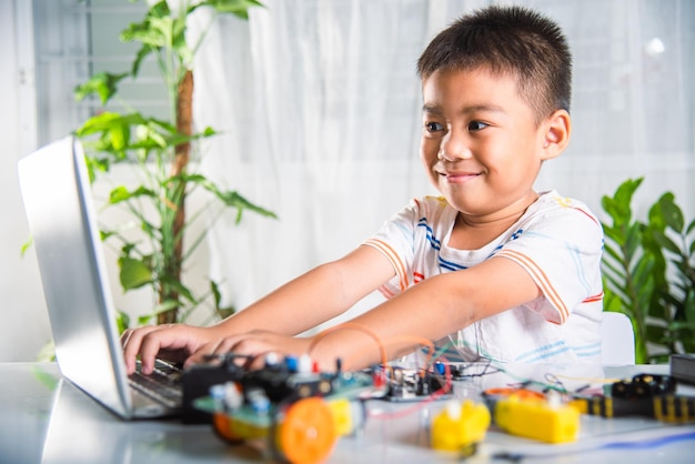Il ragazzo asiatico impara la codifica e la programmazione con il laptop per l'auto robotica Arduino