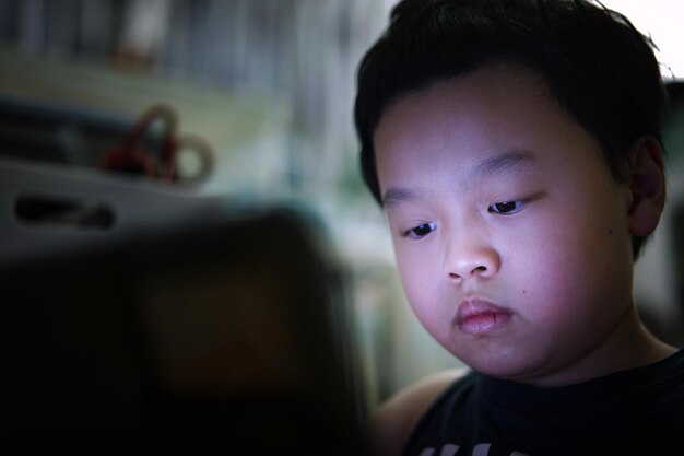 Il ragazzo asiatico impara online dal computer portatile tablet in quarantena covid 19