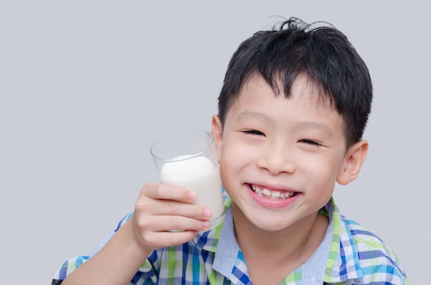 Il ragazzo asiatico sorride e tiene un bicchiere di latte