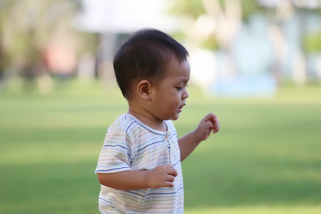 Il ragazzo asiatico sta imparando a camminare nel giardino.