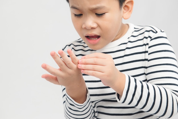 Il ragazzo asiatico tiene la mano nell'altra mano ha un graffio e scorre nel sangue che gli fa male