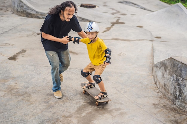 Il ragazzo atletico impara a fare skateboard con un trainer asiatico in uno skate park Sport educativi per bambini Diversità di razza