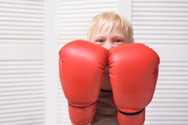 Il ragazzo biondo è protetto in due guantoni da boxe. Ritratto