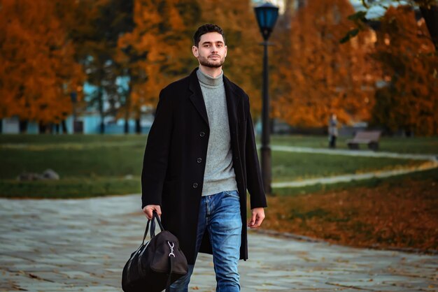 Il ragazzo cammina nel parco serale. Il ragazzo è venuto in un'altra città.