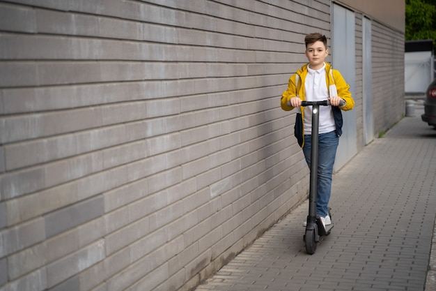 Il ragazzo cavalca su uno scooter elettrico lungo la strada della città