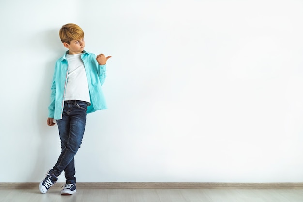 Il ragazzo che gesticola sullo sfondo del muro bianco