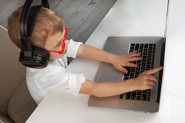 Il ragazzo che indossa le cuffie wireless e gli occhiali rossi usa il touch screen del laptop