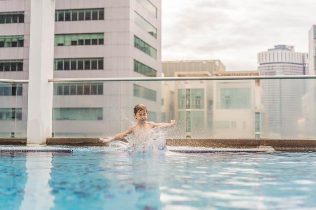 Il ragazzo che salta in piscina tra i grattacieli e la grande città si rilassa nella grande città da cui riposa