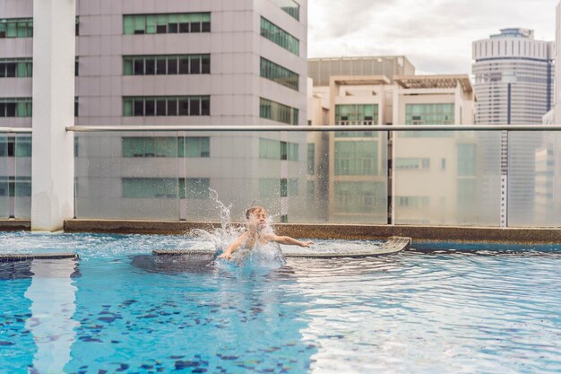 Il ragazzo che salta in piscina tra i grattacieli e la grande città si rilassa nella grande città da cui riposa