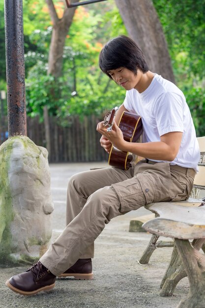 Il ragazzo che suona la chitarra, all&#39;aperto, pantaloni cargo