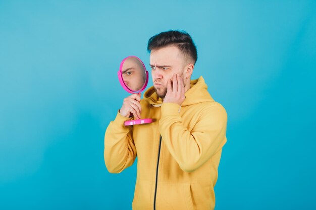 il ragazzo con la felpa gialla si guarda allo specchio rosa