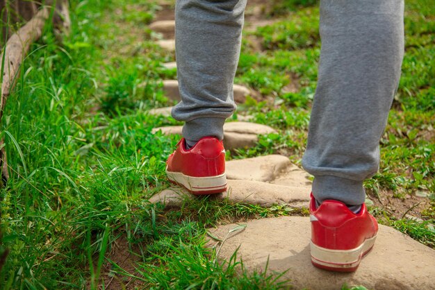 Il ragazzo con le scarpe da ginnastica rosse che cammina sul vecchio sentiero di pietra