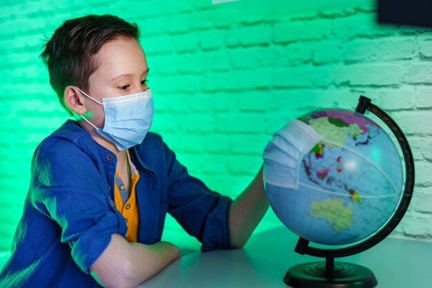 Il ragazzo con una maschera medica tiene un globo in una maschera protettiva