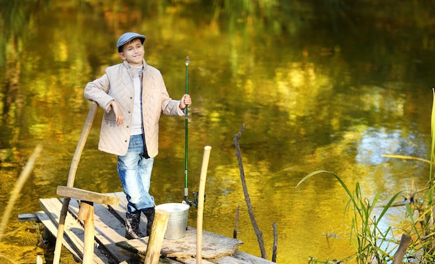 Il ragazzo con una rete da pesca è appoggiato su una ringhiera di legno del bacino