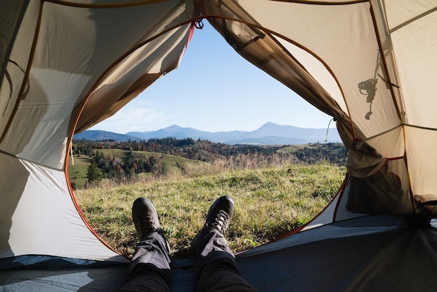 Il ragazzo contempla la vista delle montagne da una tenda turistica durante un'escursione in montagna