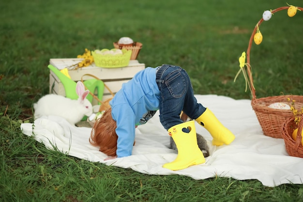 Il ragazzo dai capelli rossi sta giocando con i conigli nel parco primaverile e c'è un sacco di decorazioni pasquali