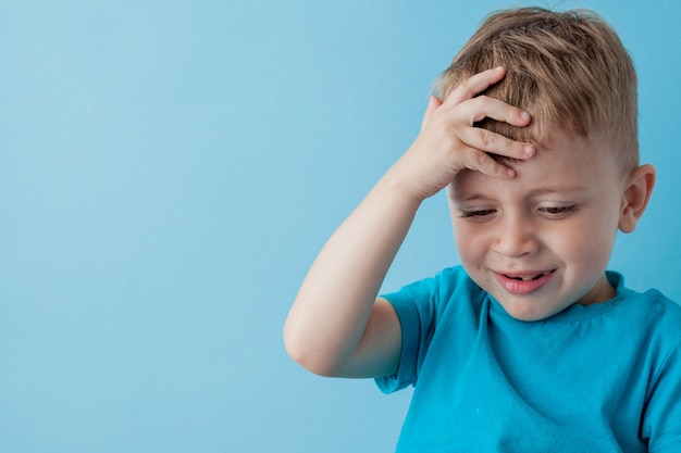 Il ragazzo del bambino 2-3 anni che indossa i vestiti blu tiene la leva di comando a disposizione per il ritratto blu dello studio dei bambini del fondo del gameson. Concetto di lifestyle di infanzia di persone. Mock up copia spazio