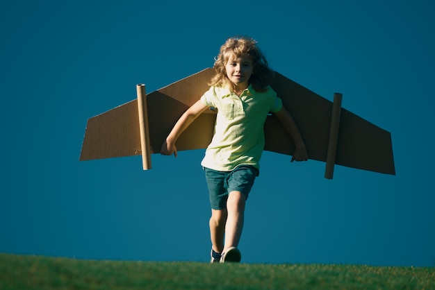 Il ragazzo del bambino come un pilota con le ali del giocattolo contro il cielo blu il concetto di libertà dei bambini sogna di diventare un pil