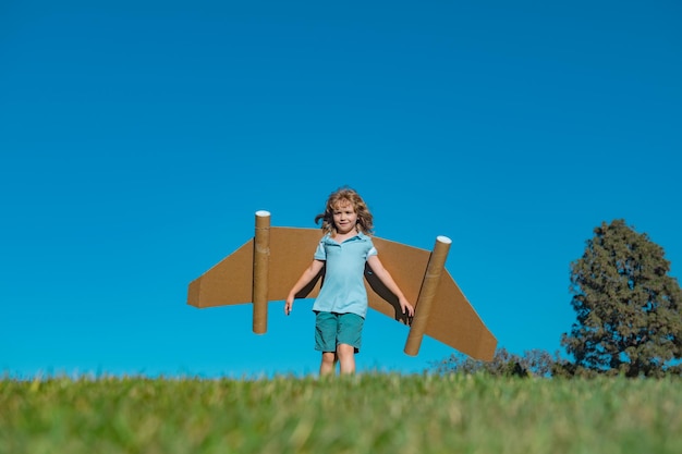 Il ragazzo del bambino gioca in un astronauta sogna di spazio il bambino felice gioca con le ali di cartone dell'aereo giocattolo di nuovo