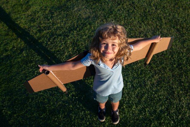 Il ragazzo del bambino sogna e viaggia Ragazzo con il giocattolo dell'aeroplano all'aperto Bambino felice che gioca con l'aeroplano giocattolo all'aperto nel campo estivo Concetto di vacanza e libertà di viaggio