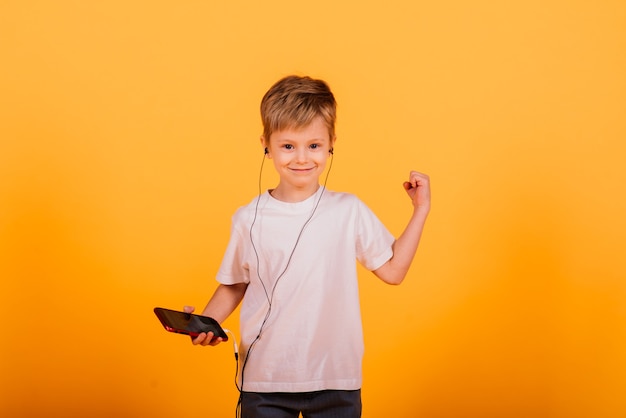 Il ragazzo delle emozioni ascolta musica con le cuffie sul suo telefono, parete gialla.