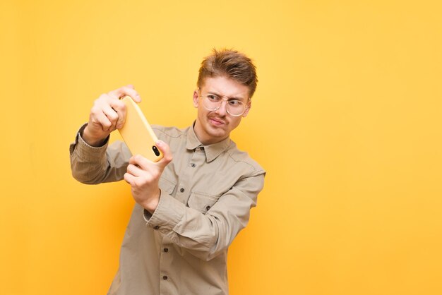 Il ragazzo divertente del giocatore si sta concentrando sulla riproduzione di giochi mobili isolati